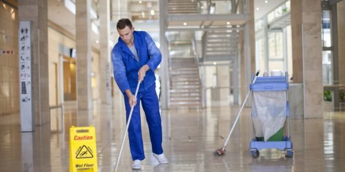 Male cleaner mopping in office atrium